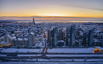 Snowy city roads and apartment buildings during sundown