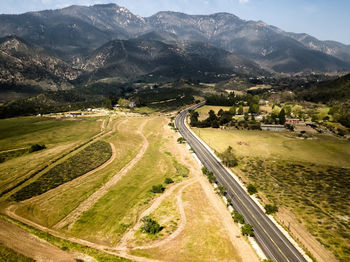 High angle view of road amidst field against mountains
