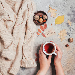 Cropped hand of woman holding tea over sweater