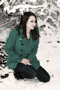 Young woman sitting on snow covered land