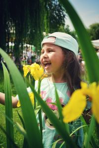 Close-up of girl looking down while standing on yellow flowering plants