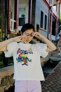 Side view of young woman standing against wall