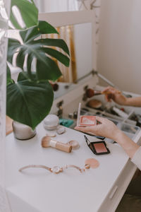 Cropped hands of woman holding beauty products on table at home