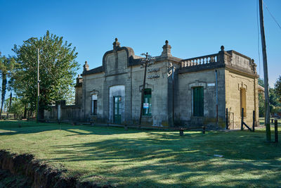 Lawn by building against blue sky