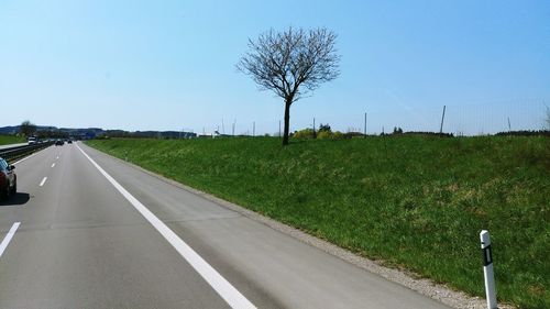 Road amidst field against clear sky