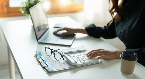 Midsection of woman using laptop on table