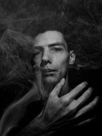 Portrait of young man against black background