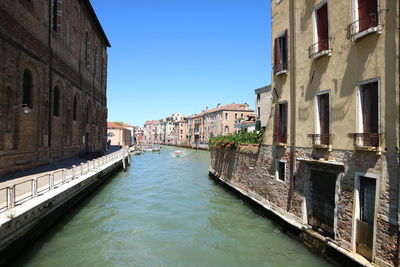 Canal amidst buildings in city against clear sky