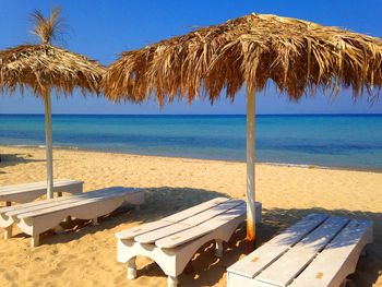 Lounge chairs and parasols on beach against sky