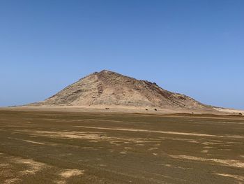 Scenic view of arid landscape against clear blue sky