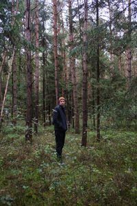 Full length of man standing by trees in forest