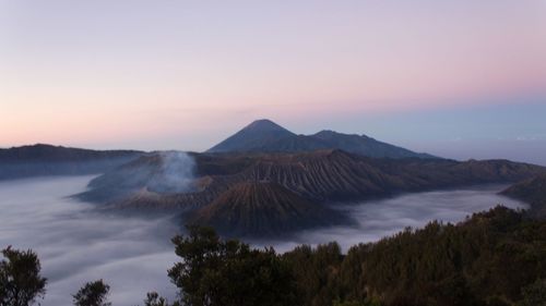 Scenic view of volcanic mountain against sky during sunset