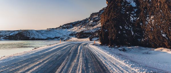 Road leading towards snow covered mountain against sky