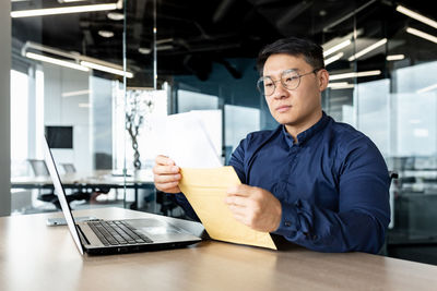 Portrait of young man using mobile phone in office