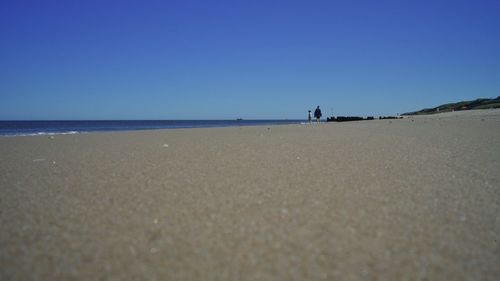 Scenic view of beach against clear blue sky