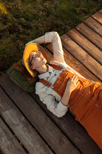 Woman naturalist resting lying on a backpack on wooden path through peat bog swamp in national park