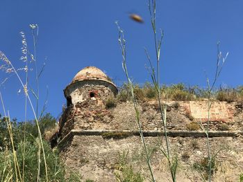 Low angle view of abandoned building against clear blue sky