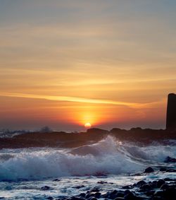 Waves splashing on rocks at sunset