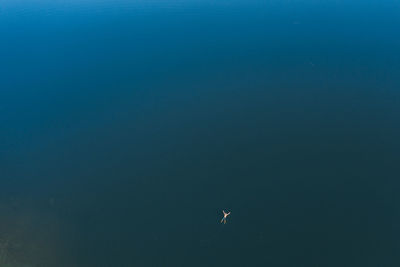 Man rest on sea waters, lie with legs and hands stretched out, top-down aerial shot. 