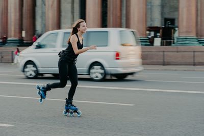 Full length of man skateboarding on street in city