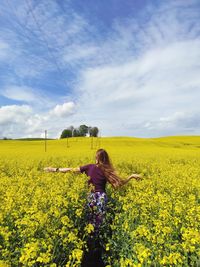 Woman standing in field with yellow flowers in background