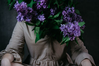 Close-up of person holding bouquet against purple flowering plants