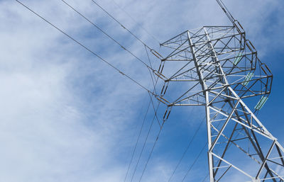 Low angle view of electricity pylon against blue sky