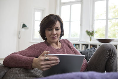 Woman at home sitting on the sofa using tablet