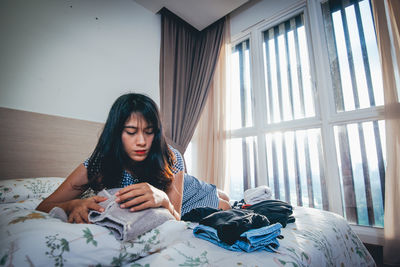 Tired young woman lying on bed at home