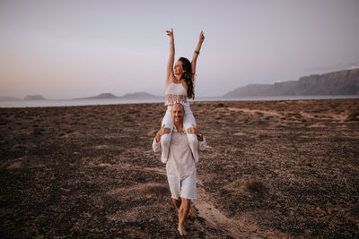 Woman with arms raised standing on land