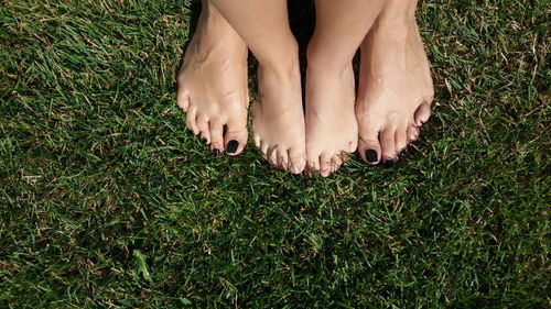 Low section of friends standing on grassy field