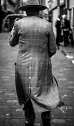 Rear view of man and woman walking on sidewalk