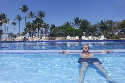 Man swimming in infinity pool against trees