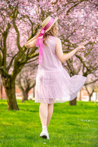 Midsection of woman with pink umbrella on grass