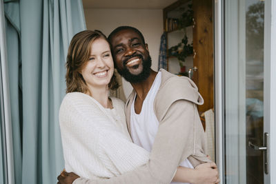 Happy multiracial couple embracing each other at doorway