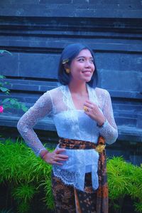 Young woman holding smiling while standing against wall