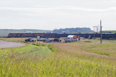 Cars on field by road against sky