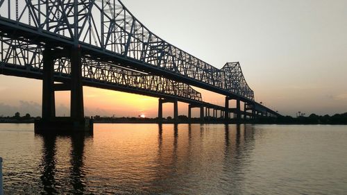 Horace wilkinson bridge over mississippi river against sky during sunset