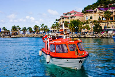 Boat moored in sea against buildings in city