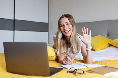 Smiling woman talking on video call on bed