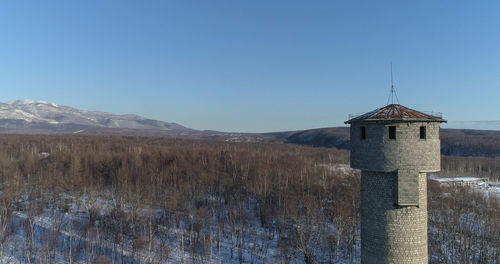 Built structure on landscape against clear blue sky