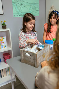 Students showing how to recycle in ecology classroom with her teacher in foreground