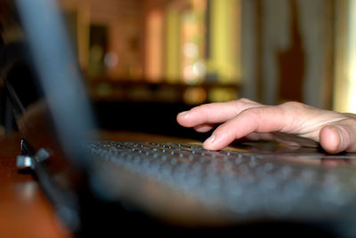 Close-up of human hand using laptop