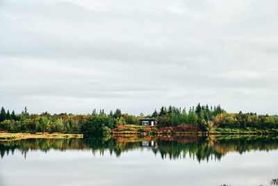 Tranquil landscape of lonely house among forest on coast of lake