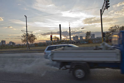 Cars on street in city against sky during sunset