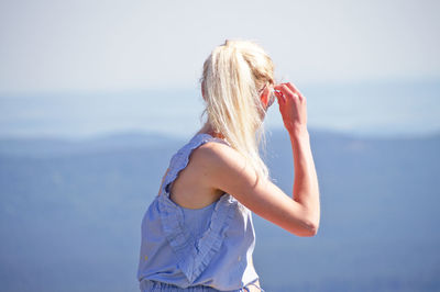 Woman sitting against sky in sunny day