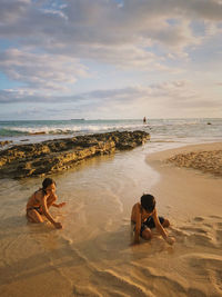 Children playing at beach against sky