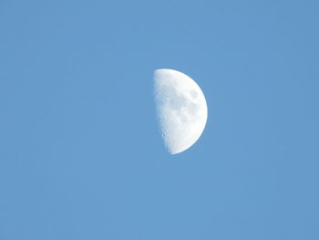 Low angle view of moon against clear blue sky