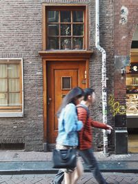 Full length side view of woman standing against building