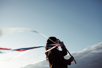 Rear view of woman with umbrella against blue sky